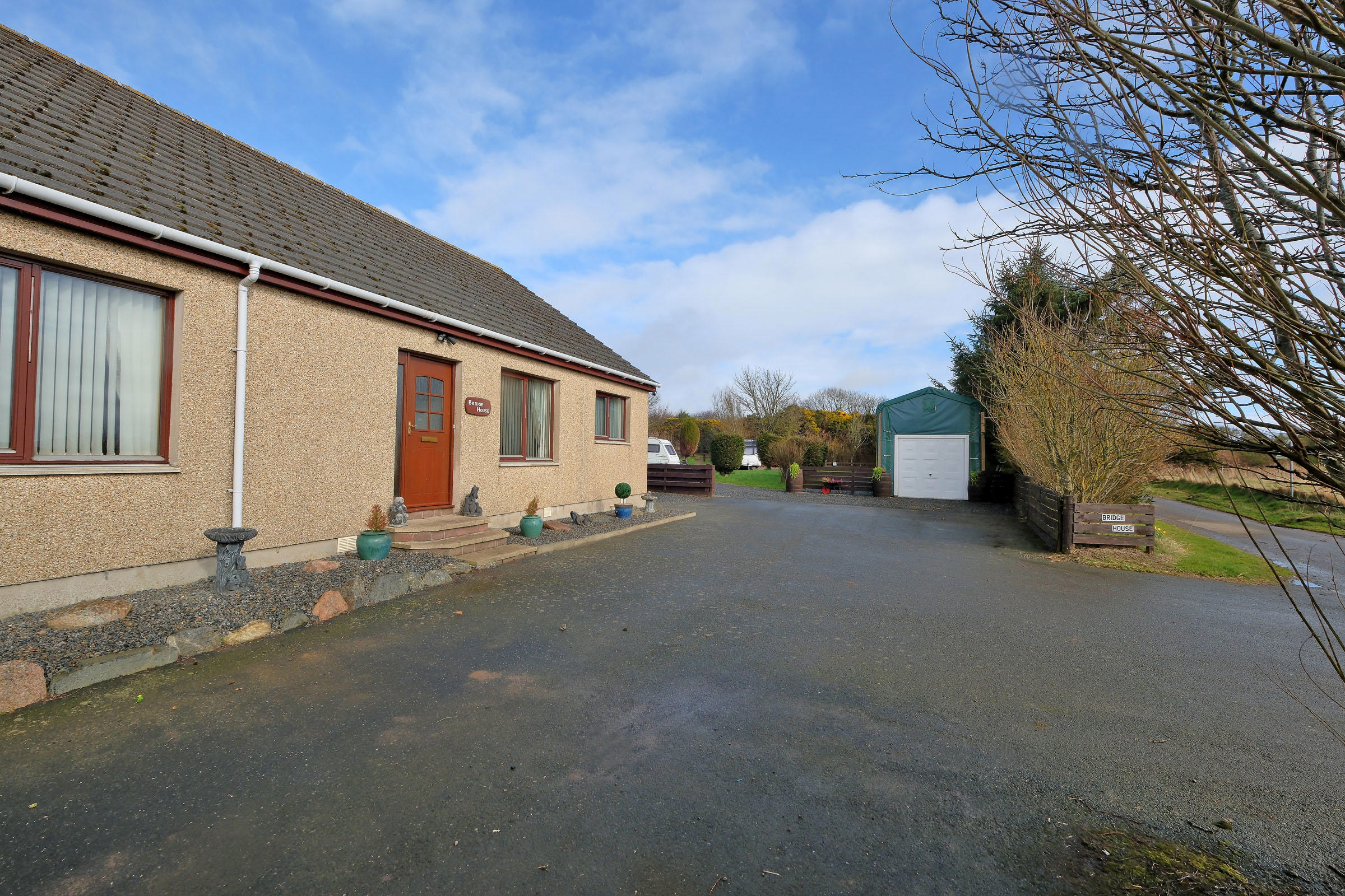 Bridge House — the property exterior with driveway and caravan site beyond