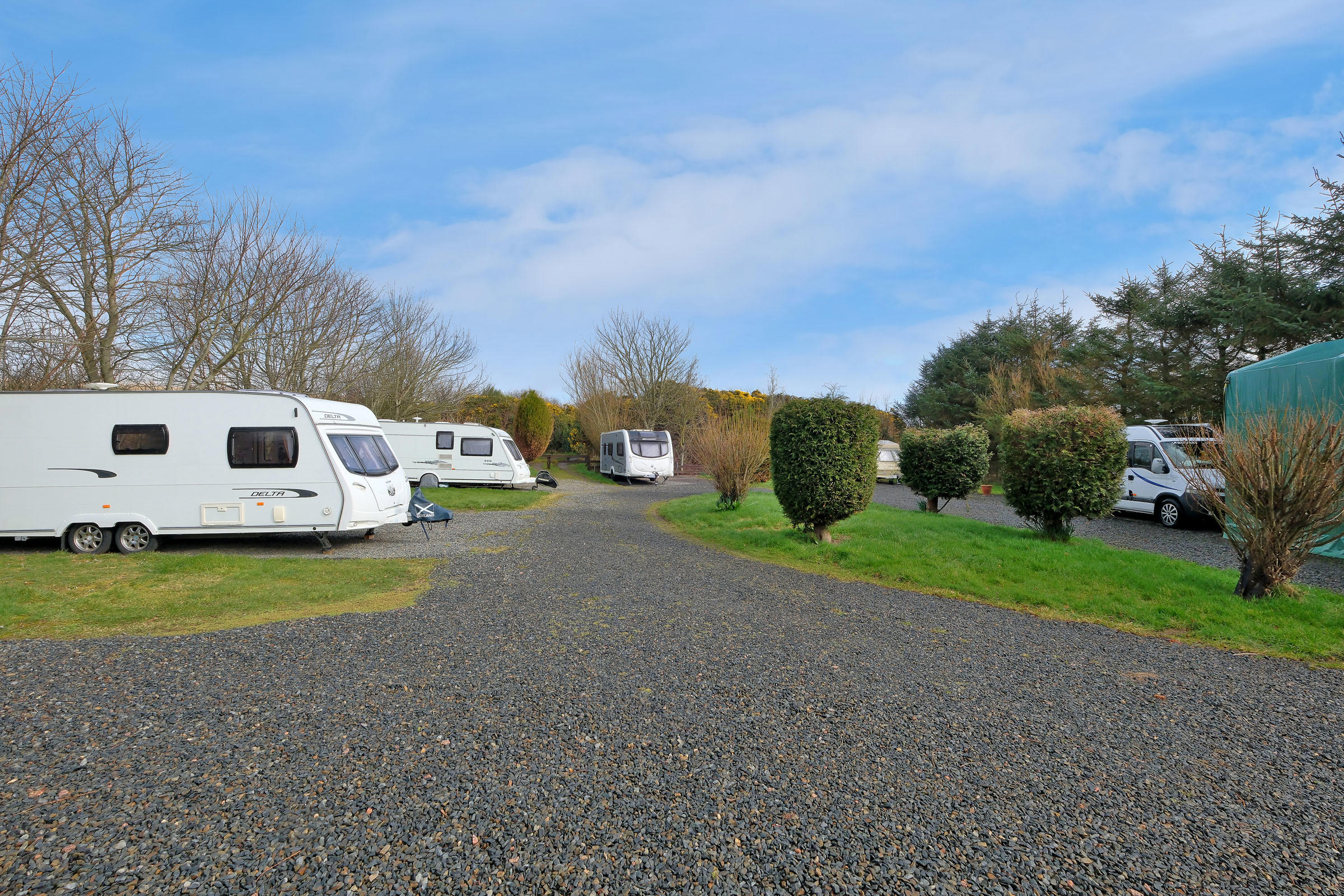 Bridge House caravan pitches with caravans and motorhomes on a sunny day